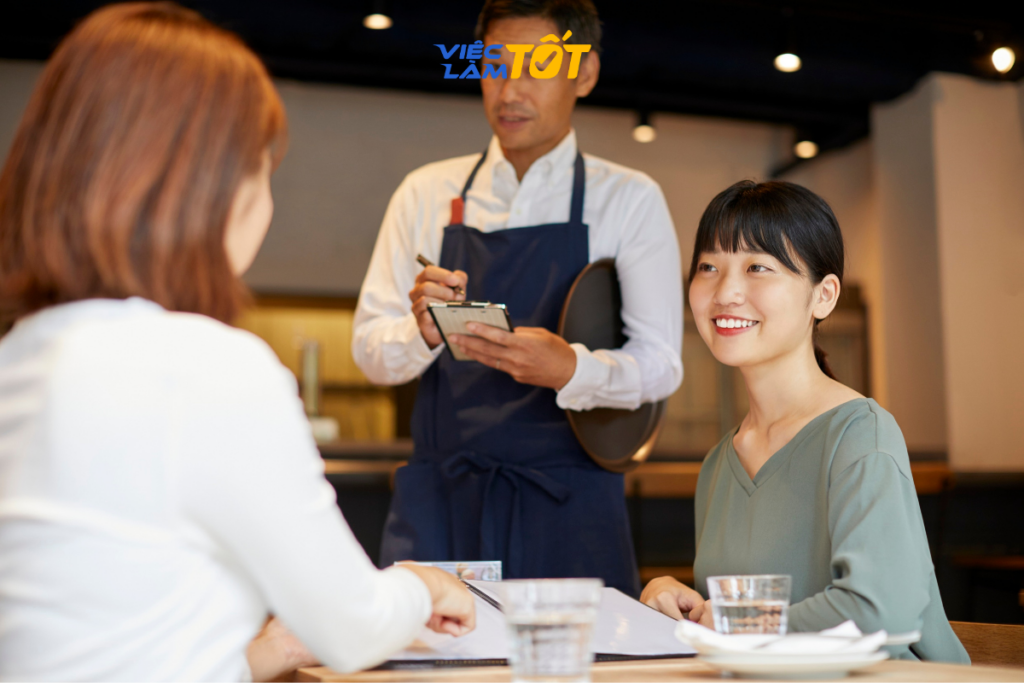 Nhân viên phục vụ dọn món và chúc khách ngon miệng