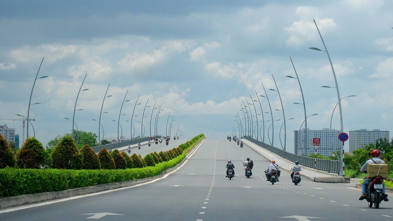 Thông tin tổng quan và các khu vực dân cư lân cận Cầu Thủ Thiêm Cầu Thủ Thiêm là một cây cầu dây văng hiện đại với một trụ chính và nhiều dây cáp, bắc qua một con sông rộng. Giữa cầu đông đúc với nhiều phương tiện giao thông như xe máy, ô tô và xe buýt. Nền cảnh là một khu đô thị với các tòa nhà cao tầng và bầu trời xanh trong.