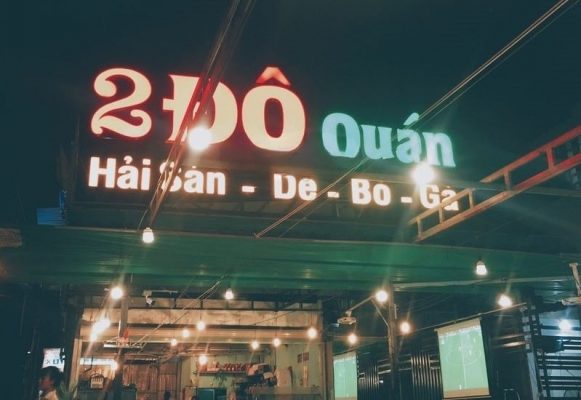 Top những Quán Nhậu Thủ Đức không thể bỏ qua sau những giờ học tập Biển hiệu của quán nhậu 2 Đô Quán, với đèn neon sáng rực, có hình vẽ của một con cua và một con ốc.