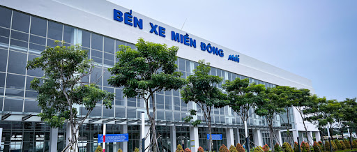 Mặt tiền của Bến xe Miền Đông mới với cây xanh bao quanh và thiết kế hiện đại, với dòng chữ "Bến xe Miền Đông mới" nổi bật trên tòa nhà.
