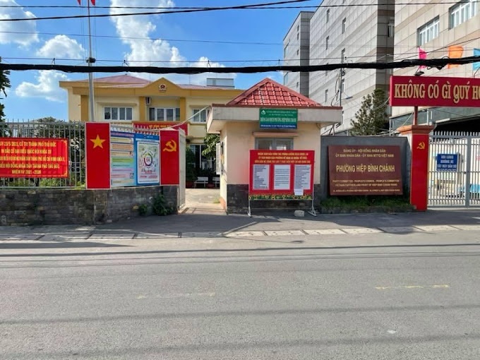 Mặt trước của Ủy ban Nhân dân phường Hiệp Bình Chánh, thành phố Thủ Đức, với tòa nhà màu vàng và lối vào mái ngói đỏ. Nhiều băng rôn với cờ Việt Nam và cờ Đảng Cộng sản Việt Nam cùng các bảng thông tin được treo ở cổng chính.