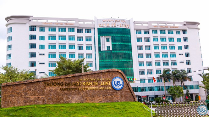 Trường Đại học Kinh tế Luật ĐHQG Tp.HCM, cánh cửa dẫn đến tương lai Tòa nhà chính của Trường Đại học Kinh tế - Luật TP.HCM, với kiến trúc hiện đại và màu trắng chủ đạo. Trước tòa nhà là một biển hiệu bằng đá với tên của trường và logo UEL.