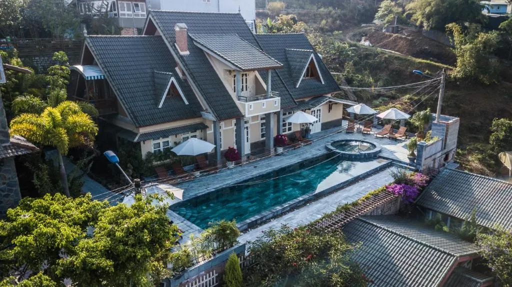 Khách sạn Đà Lạt với biệt thự mái ngói và hồ bơi ngoài trời giữa khung cảnh thiên nhiên xanh mát.