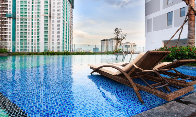 Hồ bơi căn hộ với ghế nằm thư giãn và view thành phố
