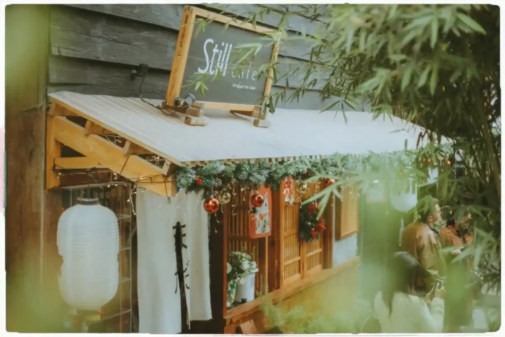 Quán cafe Đà Lạt mang phong cách Nhật Bản với mái hiên gỗ, đèn lồng trắng và trang trí Giáng Sinh tinh tế, tạo không gian ấm cúng và yên tĩnh.