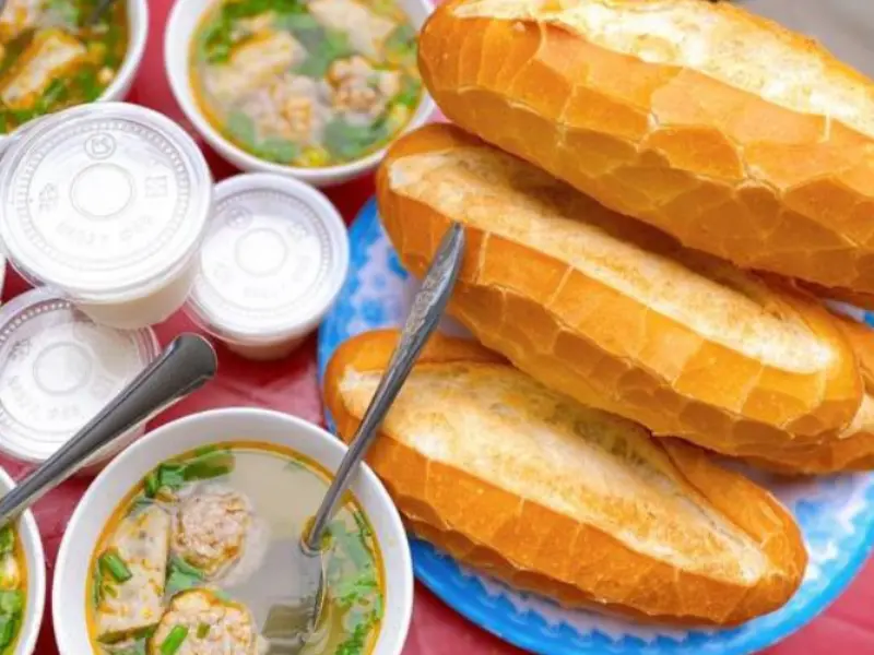 Đĩa bánh mì giòn nóng hổi ăn kèm chén xíu mại thơm ngon, đặc trưng của món bánh mì xíu mại Đà Lạt.