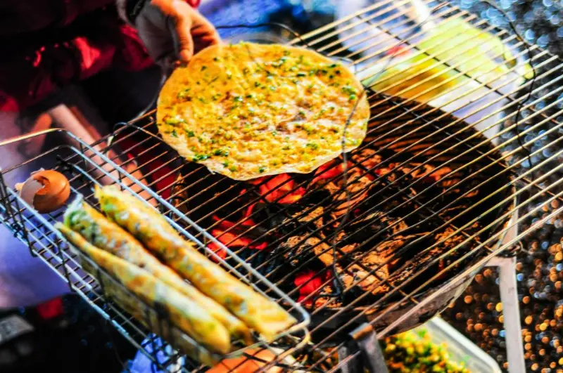 Bánh tráng nướng được rắc hành phi, tương ớt và ruốc đều tay.