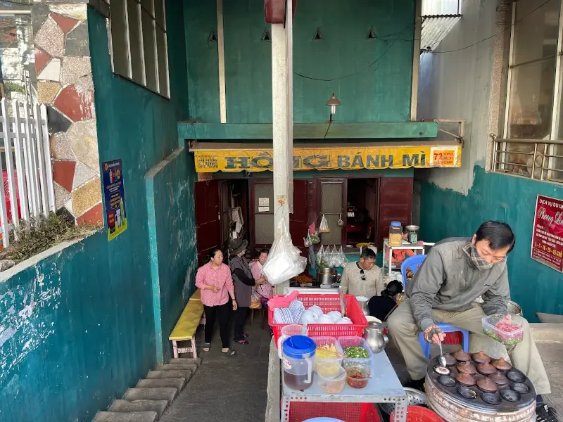 Quán bánh mì xíu mại Đà Lạt Cô Hồng nằm sâu trong hẻm với không gian mộc mạc, đông khách và bếp lò nấu xíu mại ngay lối vào.