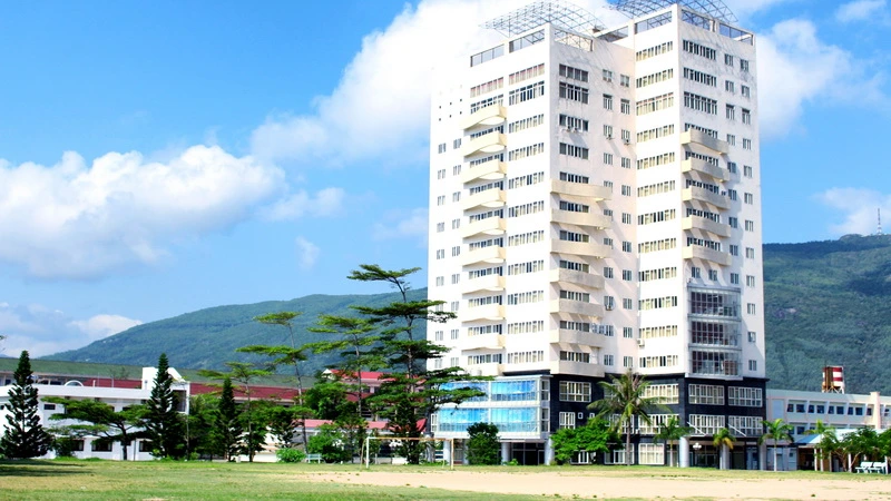 Tòa nhà cao tầng hiện đại của Trường Đại học Quy Nhơn với nền trời xanh và núi phía sau