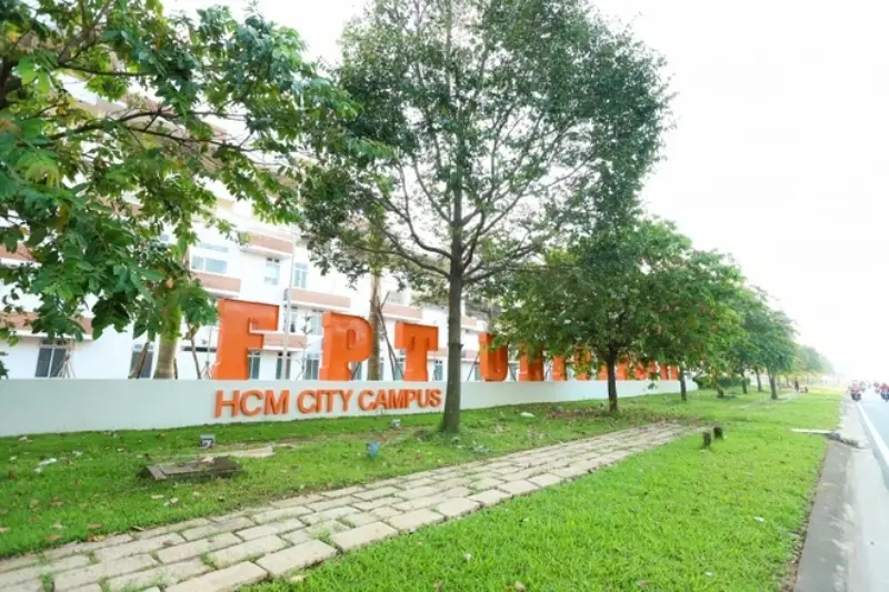 Khuôn viên Trường Đại học FPT TP.HCM với hàng chữ "FPT University" nổi bật bên đường và hàng cây xanh mát.