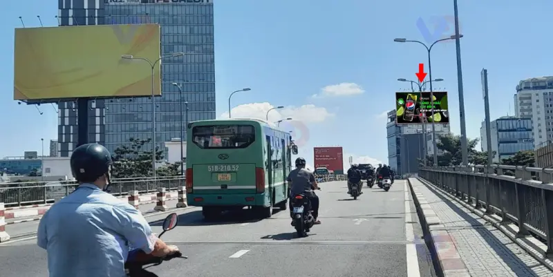 Hình ảnh xe cộ lưu thông trên Cầu Calmette, phía xa có bảng quảng cáo điện tử và các tòa nhà cao tầng.