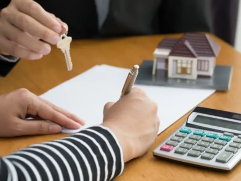 Mẹo tránh bị tăng giá thuê trọ và gợi ý cách xử lý tình huống Người thuê nhà đang ký hợp đồng thuê trọ, bên cạnh có chìa khóa và mô hình nhà tượng trưng cho giao dịch bất động sản, minh họa mẹo tránh bị tăng giá thuê trọ.