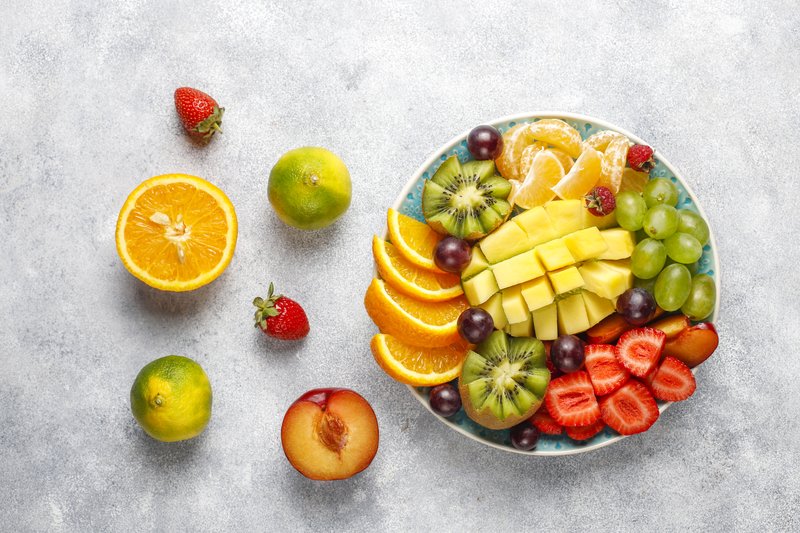 đĩa trái cây tươi gồm cam, kiwi, dâu, nho, xoài, tượng trưng cho sự đủ đầy và tươi mới trong cuộc sống.