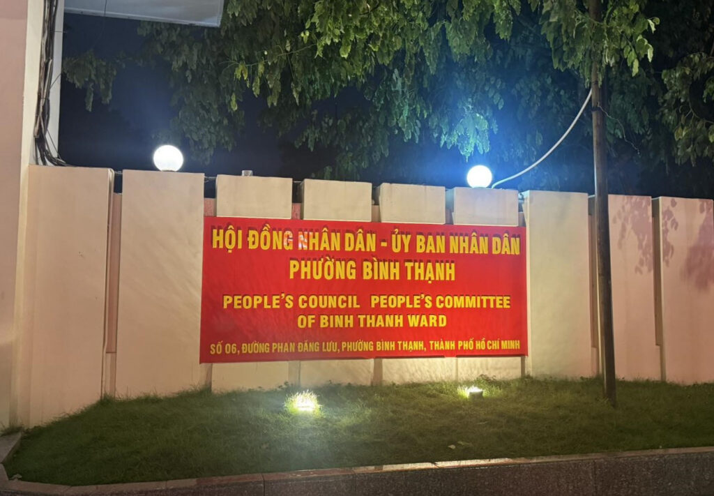 bảng hiệu UBND phường Bình Thạnh vào buổi tối với hệ thống đèn chiếu sáng, nổi bật trên nền tường phía sau.