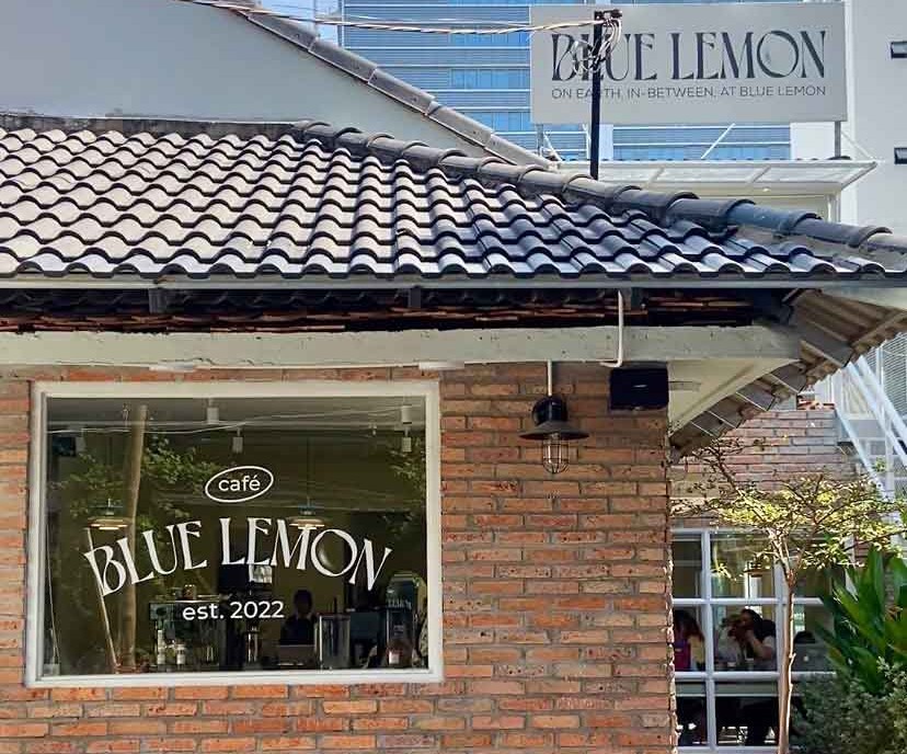 Mặt tiền quán Blue Lemon Cafe xây gạch trần, mái ngói, có cửa sổ kính nhìn vào bên trong.