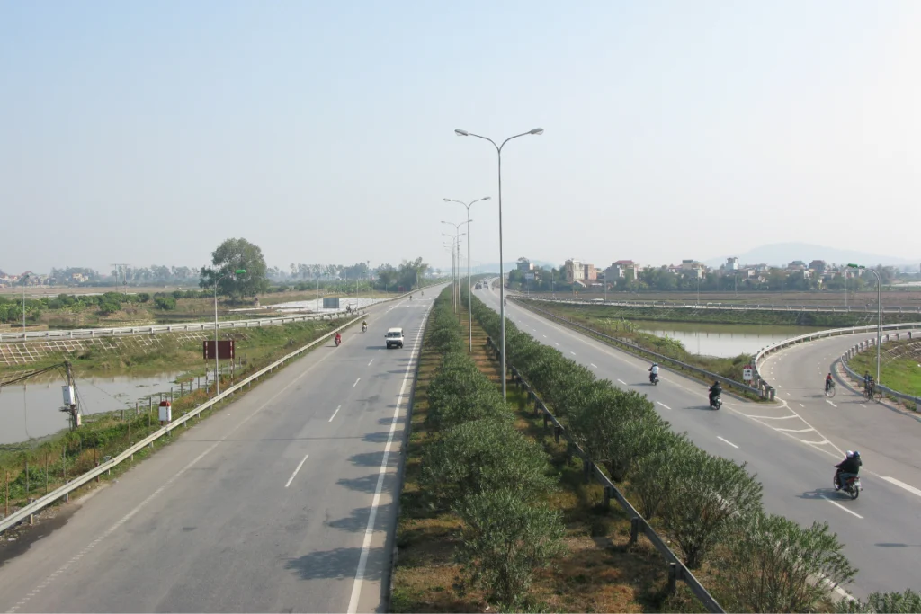 Hình ảnh trục Quốc lộ 1A khang trang với dải phân cách cứng và hệ thống biển báo, đèn chiếu sáng đồng bộ