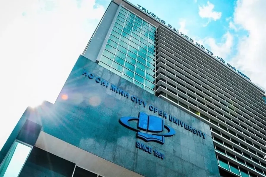 Tòa nhà Đại học Mở TP.HCM nhìn từ dưới lên với mặt tiền kính xanh và logo trường