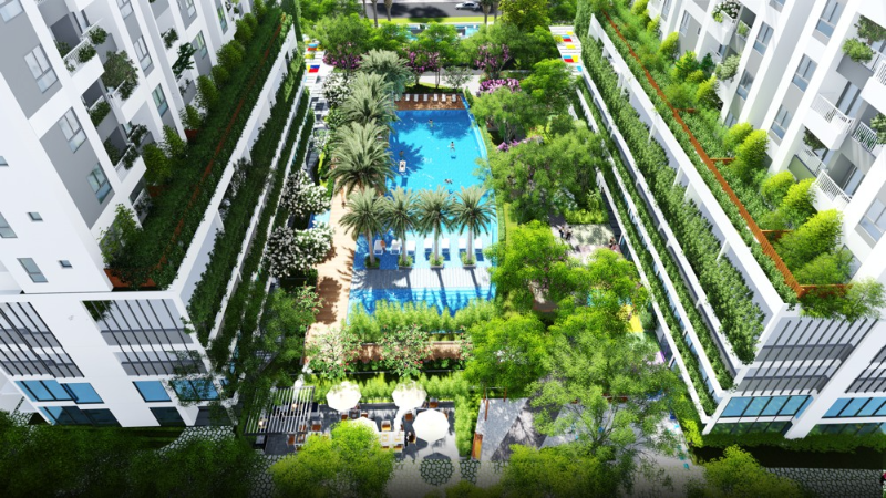 Góc nhìn từ trên cao xuống khu tiện ích nội khu của dự án với hồ bơi trung tâm, hàng cây ven bờ và ban công phủ mảng xanh của hai tòa nhà