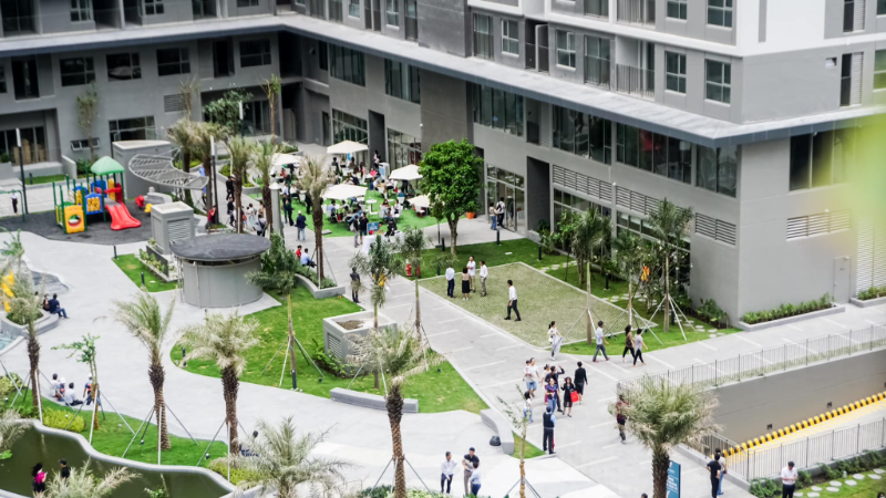 Cảnh cư dân sinh hoạt tại sân chơi nội khu chung cư với cây xanh, ghế ngồi và khu vui chơi trẻ em