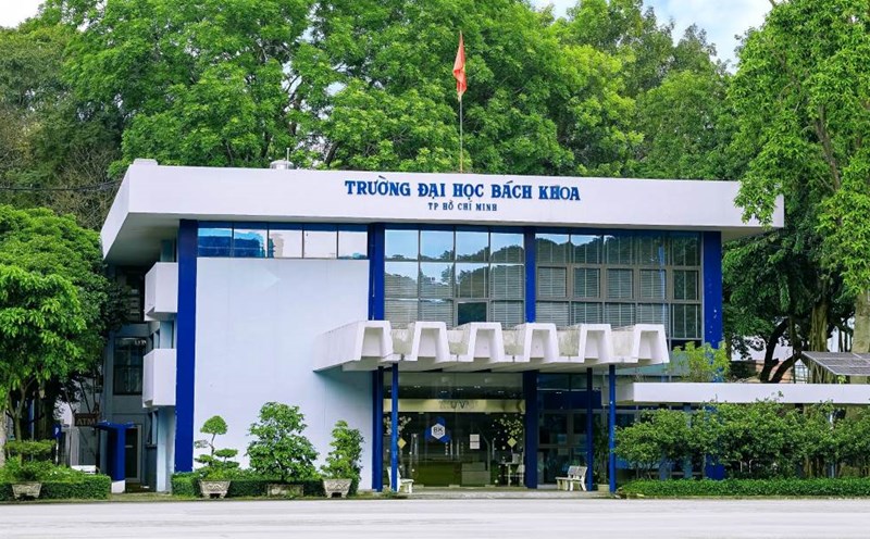 Cổng vào Trường Đại học Bách khoa TP Hồ Chí Minh với bảng tên màu xanh dương nổi bật trên nền trắng, xung quanh cây xanh