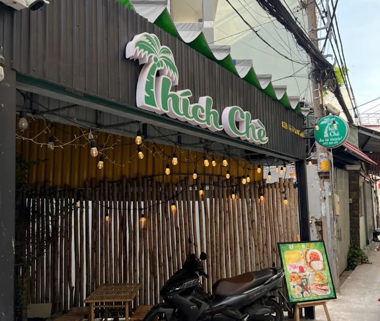 Mặt tiền quán Thích chè với biển hiệu lớn màu vàng và quầy kính trưng bày các loại nguyên liệu nấu chè sạch sẽ.