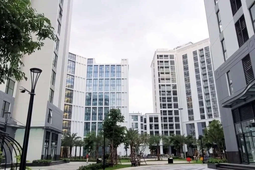 Khuôn viên nội khu hiện đại của một dự án nhà ở xã hội kiểu mẫu với các block tòa nhà cao tầng màu trắng xám bao quanh khoảng sân chung được quy hoạch đồng bộ
