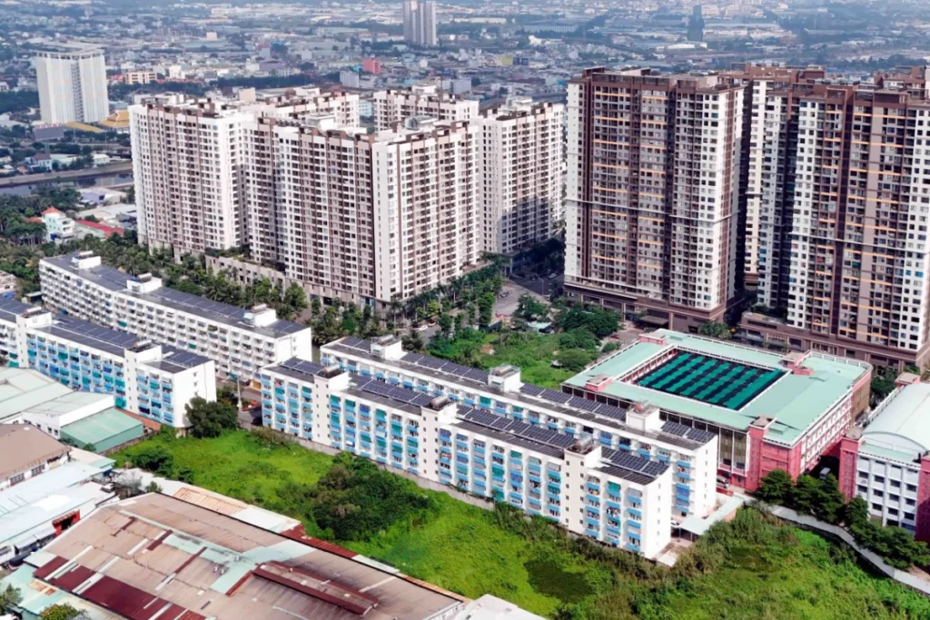 Góc nhìn từ trên cao xuống tổ hợp khu đô thị hiện đại gồm các block chung cư cao tầng đan xen khu nhà thấp tầng mái tôn xanh và khuôn viên trường học