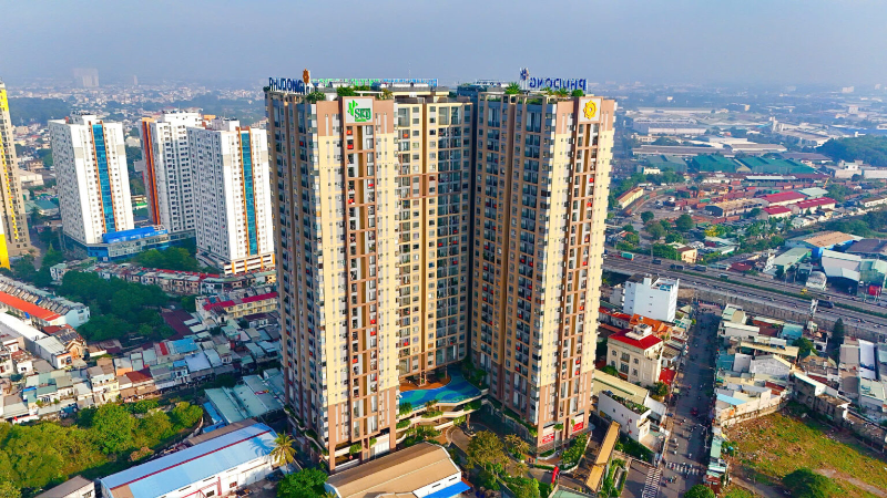 Góc chụp flycam toàn cảnh cụm chung cư Phú Đông Sky Garden sơn màu nâu beige hiện đại nằm sát rìa giao lộ giao thông sầm uất giáp ranh TP.HCM.