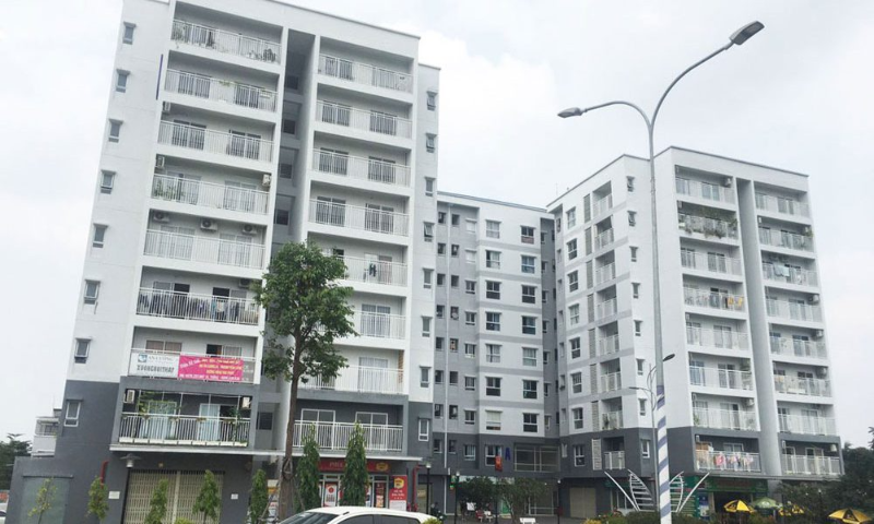 Hình ảnh thực tế mặt ngoài tòa tháp chung cư EHomeS Thủ Đức với thiết kế ban công sơn trắng xám, tầng trệt kinh doanh shophouse và hệ thống cột đèn đường
