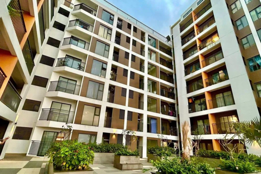 Góc nhìn cận cảnh từ dưới lên một block căn hộ hiện đại với thiết kế ô vuông bàn cờ đan xen giữa mảng tường sơn trắng và nâu kem