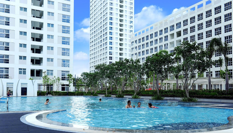Cảnh cận cảnh một hồ bơi lớn, trong xanh trong khuôn viên một khu chung cư Phú Mỹ Hưng Quận 7 với người dân đang bơi lội và thư giãn. Các tòa nhà cao tầng trắng hiện đại và cây xanh bao quanh, thể hiện lối sống đẳng cấp tại một chung cư Phú Mỹ Hưng Quận 7 nên mua.