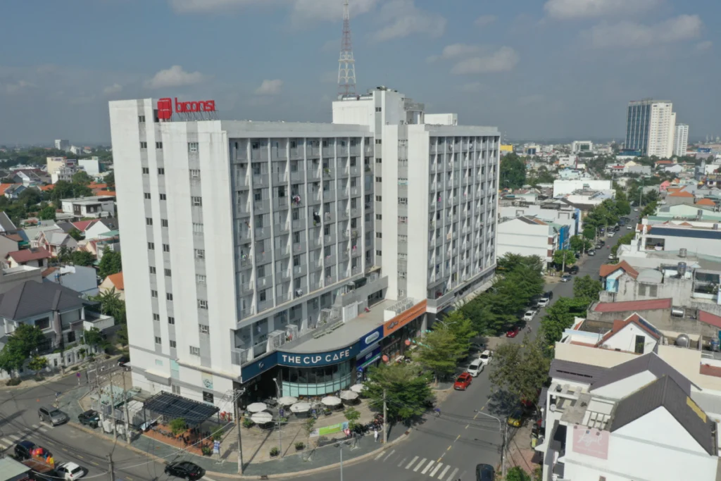 Ảnh chụp từ trên cao của tòa nhà chung cư Phú Hòa Lợi cao khoảng 10-12 tầng mang biển hiệu Biconsi màu đỏ trên nóc khối nhà sơn trắng xám