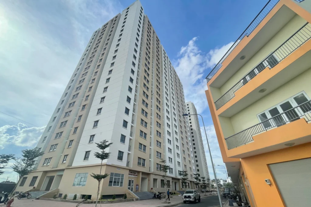 Góc nhìn từ dưới lên một block căn hộ chung cư cao tầng đã xây dựng xong phần thô và sơn hoàn thiện mặt ngoài với hai tông màu trắng và be