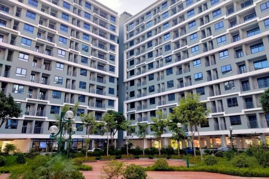 Góc nhìn chính diện hai khối tòa nhà chung cư xây dựng theo hình chữ V đối xứng nhau, ở giữa là khuôn viên sân nội khu có nhiều cây xanh và lối đi dạo lót gạch sạch sẽ