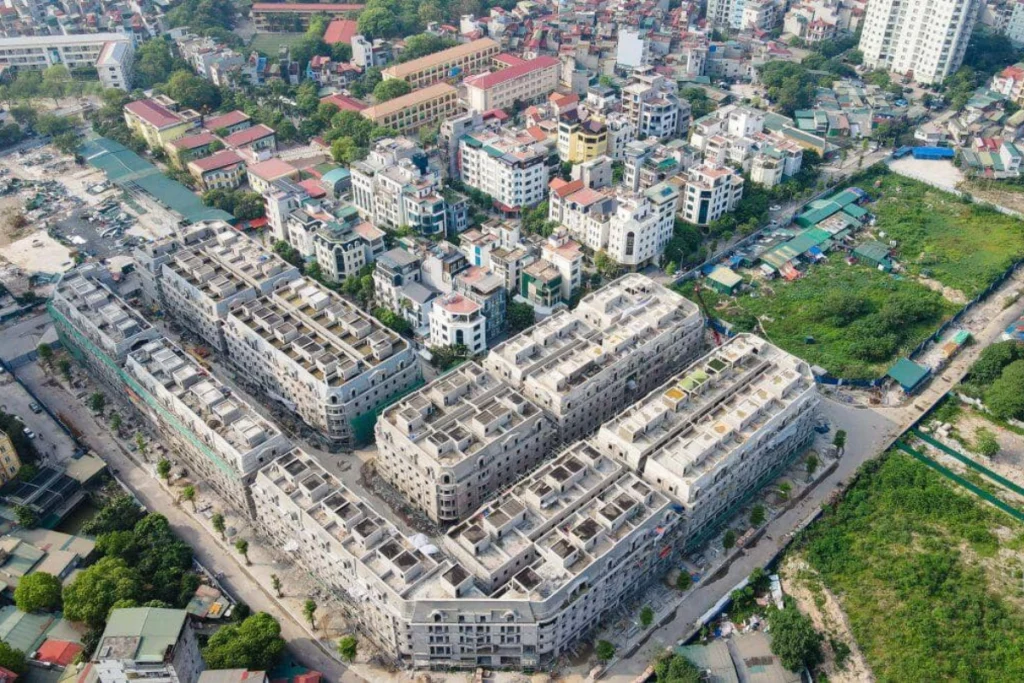 Ảnh chụp từ trên cao toàn cảnh công trường dự án đang thi công xây dựng phần thô với các khối nhà thấp tầng vuông vắn xếp cạnh nhau