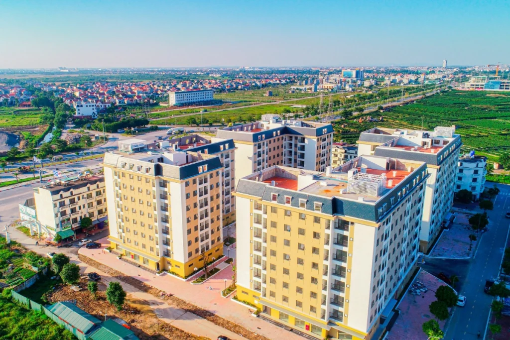 Góc nhìn từ trên cao của một khu dự án chung cư gồm 4 block nhà vuông vắn, sơn vàng nhạt tọa lạc giữa không gian xanh