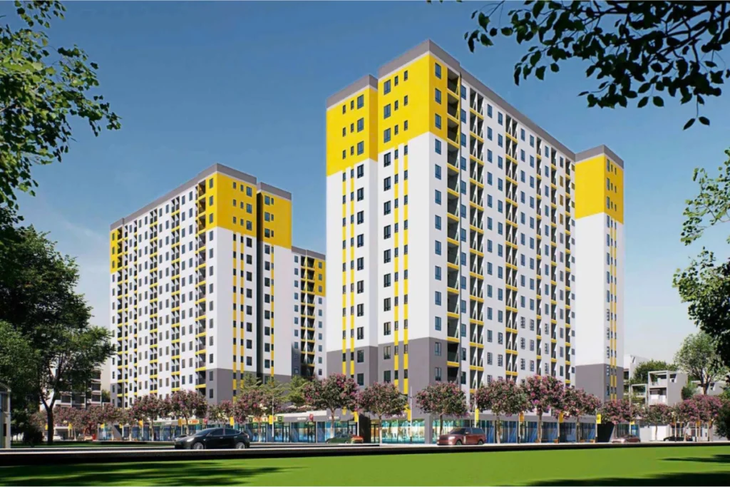 Nhà ở xã hội Bình Dương: Danh sách dự án mới Phối cảnh các khối tòa nhà chung cư cao tầng có điểm nhấn sơn màu vàng nổi bật ở phần mái, phía trước có đường lớn và hàng cây xanh, minh họa cho dự án nhà ở xã hội bình dương