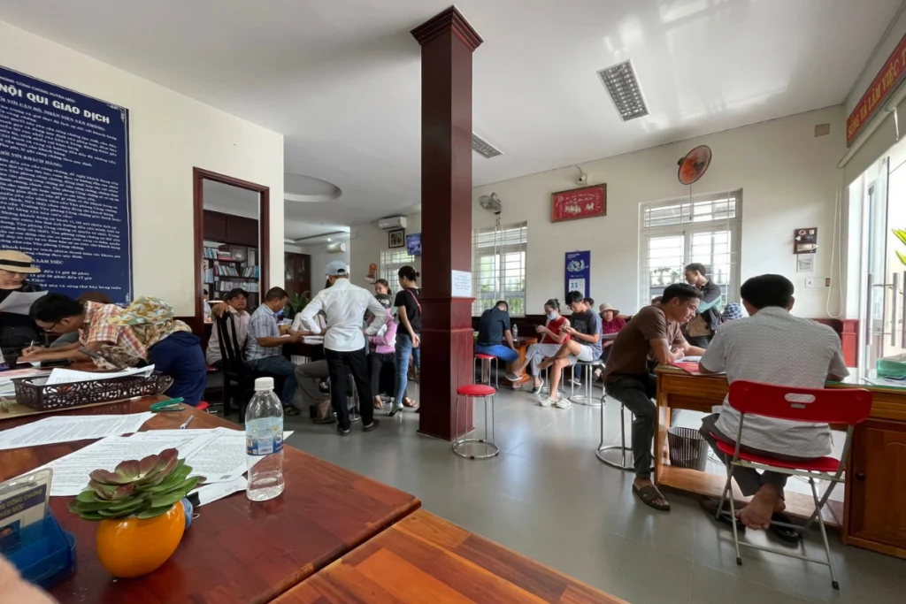 Người dân đang chờ làm thủ tục và điền thông tin hồ sơ tại sảnh giao dịch của văn phòng công chứng