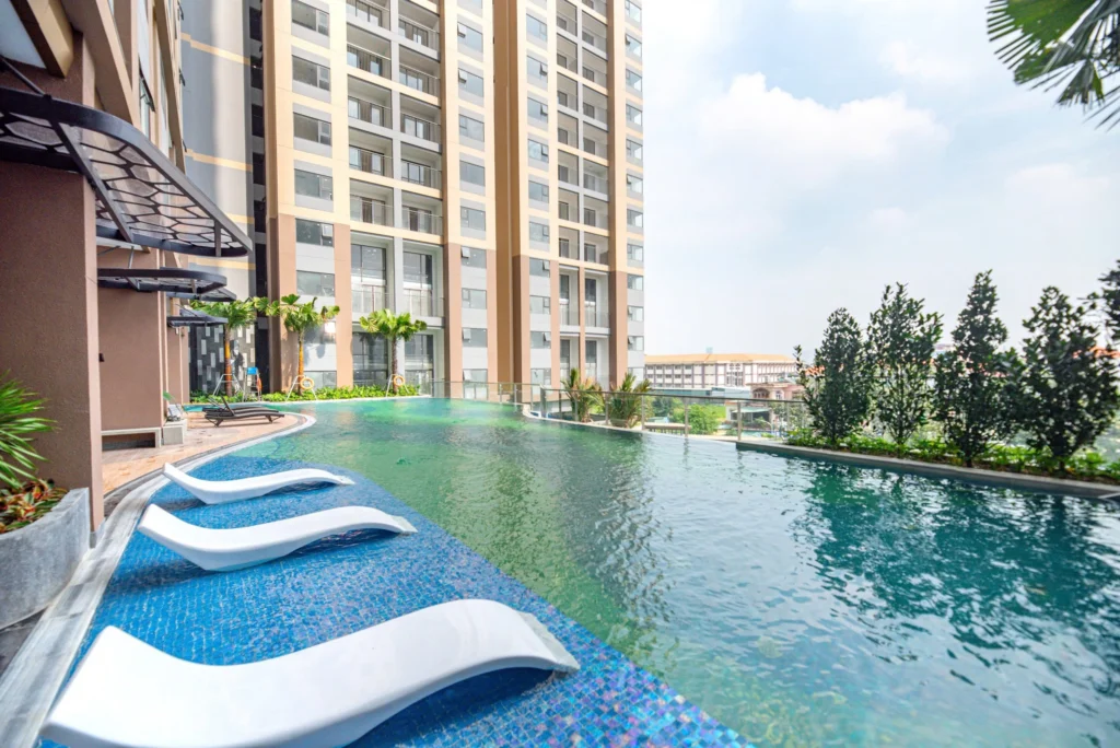 Hình ảnh thực tế hồ bơi tràn bờ hiện đại tại tầng tiện ích của một khu chung cư Bình Dương với các hàng ghế thư giãn màu trắng chìm dưới nước