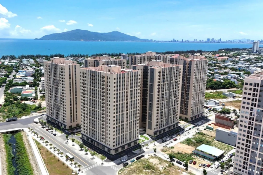 Toàn cảnh tổ hợp các block chung cư nhà ở xã hội hiện đại xây dựng sát bờ biển với tầm nhìn hướng ra vịnh biển xanh và núi non phía xa