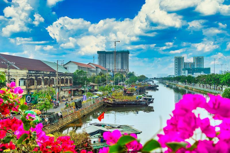 Phong cảnh bến Bình Đông yên bình dưới bầu trời xanh mây trắng với những chiếc thuyền chở đầy hoa kiểng ngày cận Tết