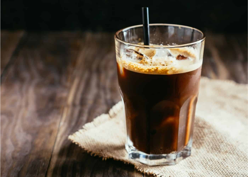 y cà phê đen đá mát lạnh đậm vị với lớp bọt mịn đặt trên bàn gỗ mộc