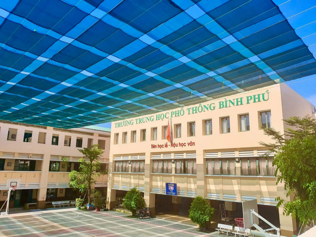 Khuôn viên sân trường khang trang và mặt tiền của Trường Trung học Phổ thông Bình Phú tại Quận 6 với dãy lớp học hiện đại dưới hệ thống mái che lưới màu xanh