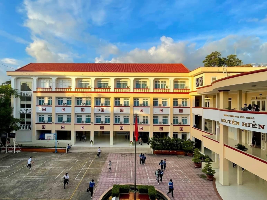 Toàn cảnh khuôn viên rộng rãi, sân bóng rổ và dãy tòa nhà học cao tầng sơn màu vàng khang trang của Trường Trung học Phổ thông Nguyễn Hiền tại Quận 11