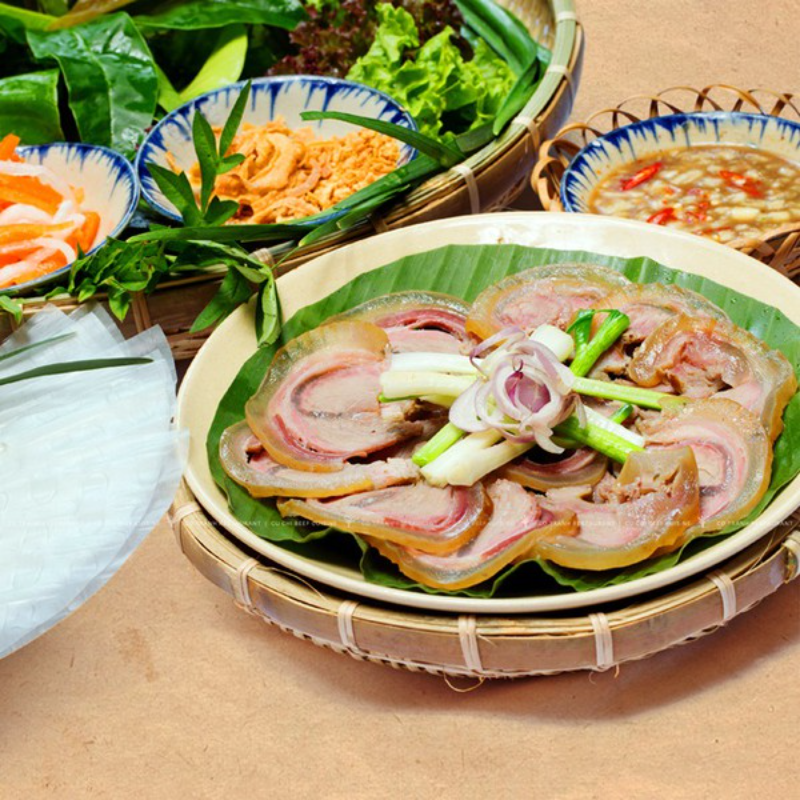 Đĩa thịt bò luộc xắt lát mỏng xếp hình hoa kèm bánh tráng, rau rừng và mắm nêm đậm đà
