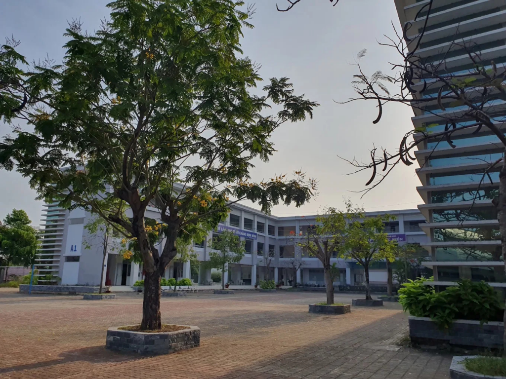 Khuôn viên sân trường THPT Phước Kiển tại huyện Nhà Bè rộng rãi và thông thoáng dưới nắng chiều, nổi bật với dãy lớp học 3 tầng khang trang