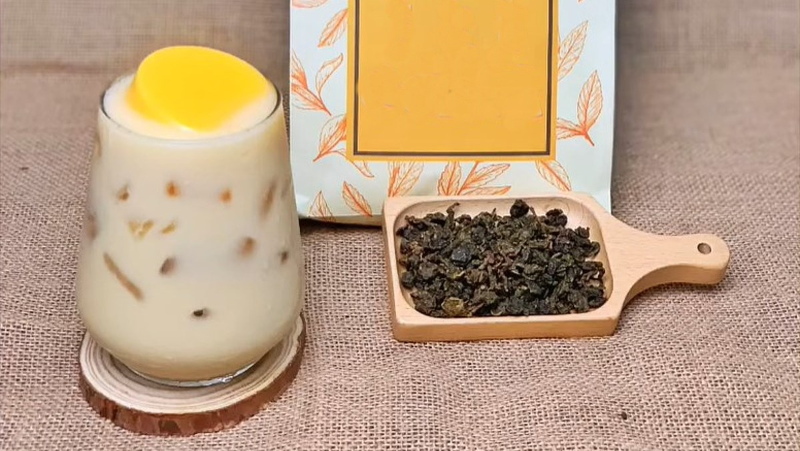 Ly trà sữa ô long kem trứng đặt cạnh lá trà ô long