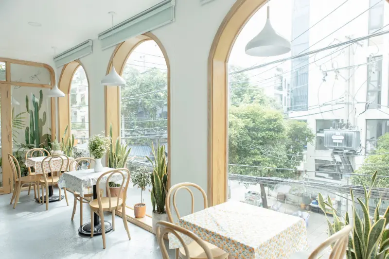 Không gian ngập tràn ánh sáng tại H2O và Tea More với dãy cửa sổ vòm gỗ lớn nhìn ra tán cây xanh và bàn ghế thiết kế tinh tế. Chốn dừng chân dịu dàng khi bạn tìm câu trả lời cho chơi gì ở phường Tân Phú.