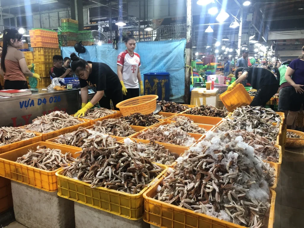 Người dân mua bán tấp nập tại vựa hải sản tươi sống với các khay càng ghẹ và cua chất đầy đá lạnh