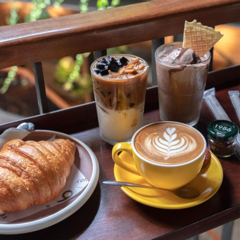 Top 9 quán cafe phường Tân Phú sở hữu không gian đẹp Khay đồ uống gồm cappuccino vẽ hình nghệ thuật, cà phê sữa đá, kem socola và bánh sừng bò croissant